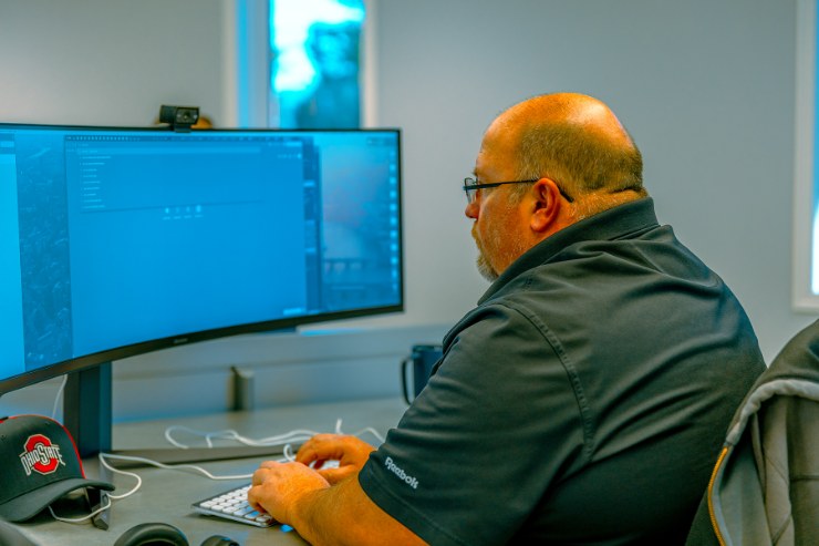 A Delta Media Group team member working at a dual-monitor workstation.