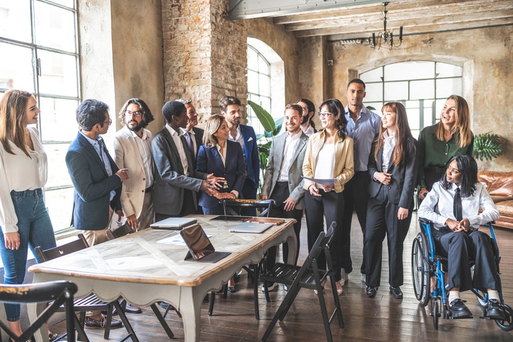 A diverse group of real estate professionals gathered around a table in a modern brokerage office.