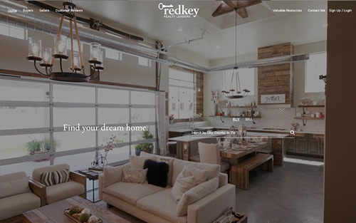 Cassie Garamella | Redkey Realty Leaders website homepage &mdash; a warm industrial-style living room and kitchen with 'Find your dream home.' over a property search bar.