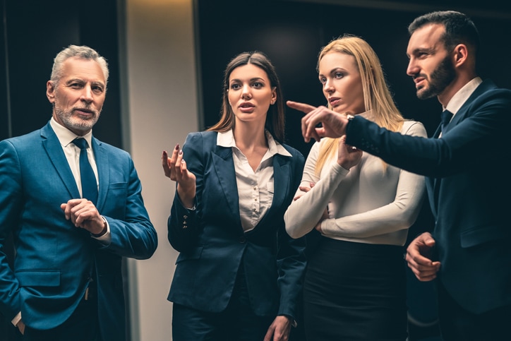 A real estate team in business attire discussing strategy together in the office.